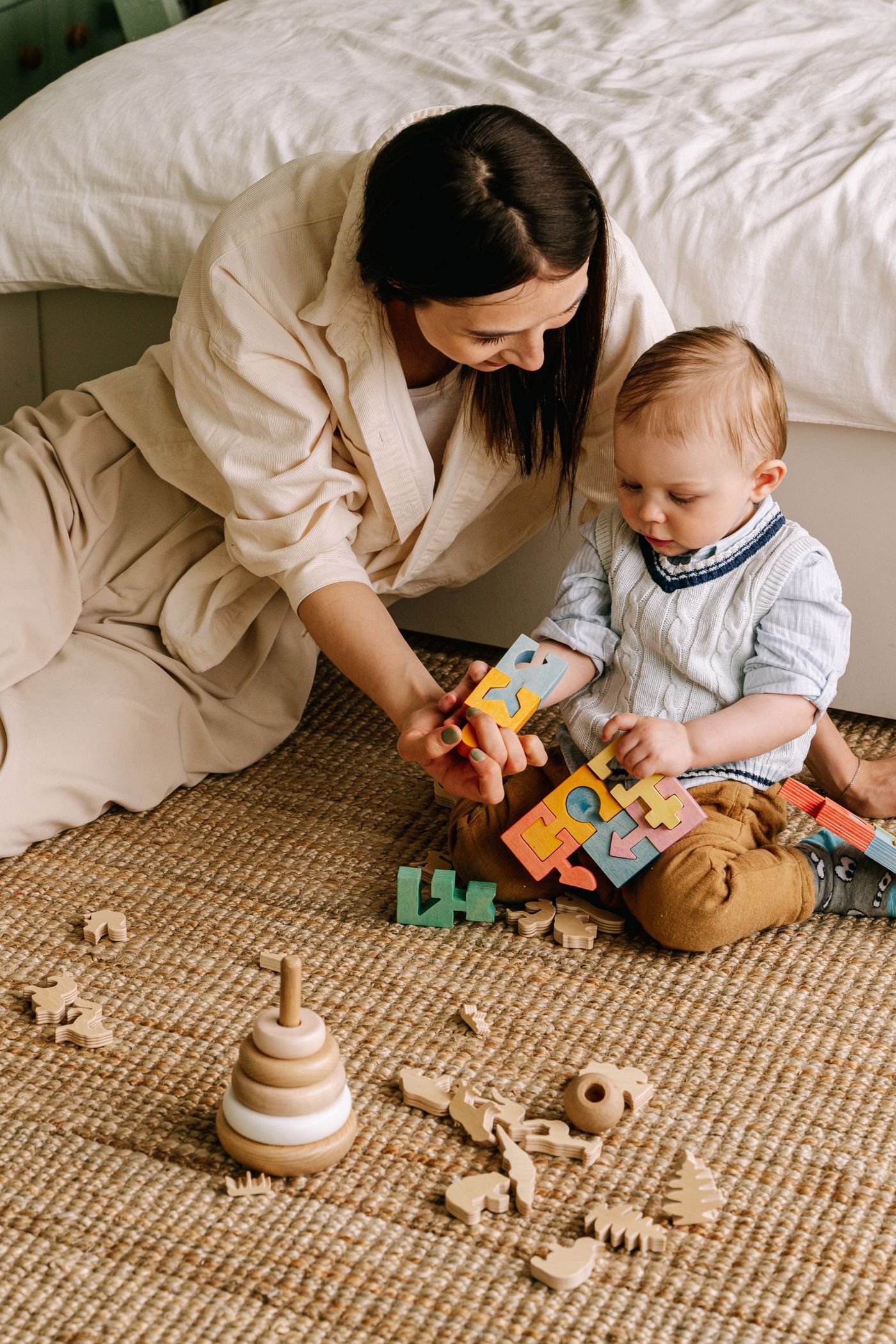 Parent and toddler playing together with soft toys on a classroom rug